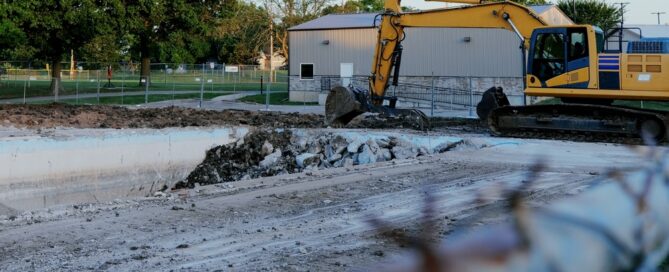 Yellow Excavator Tearing Down Swimming Pool